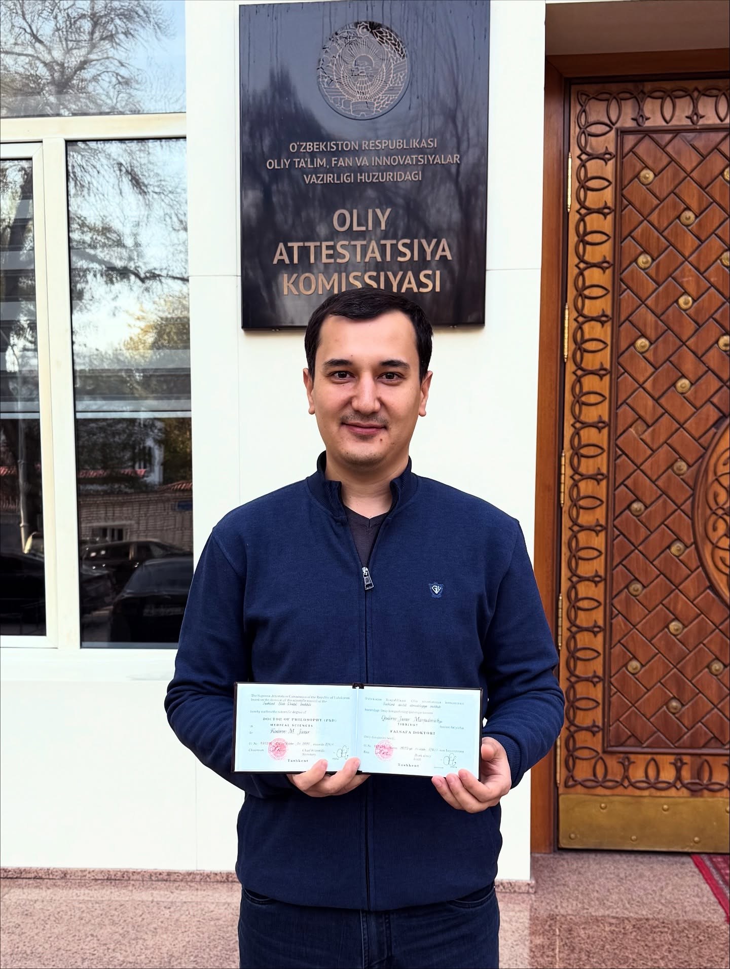Jasur Qodirov PhD diplomi bilan Oliy attestatsiya komissiyasi binosi oldida